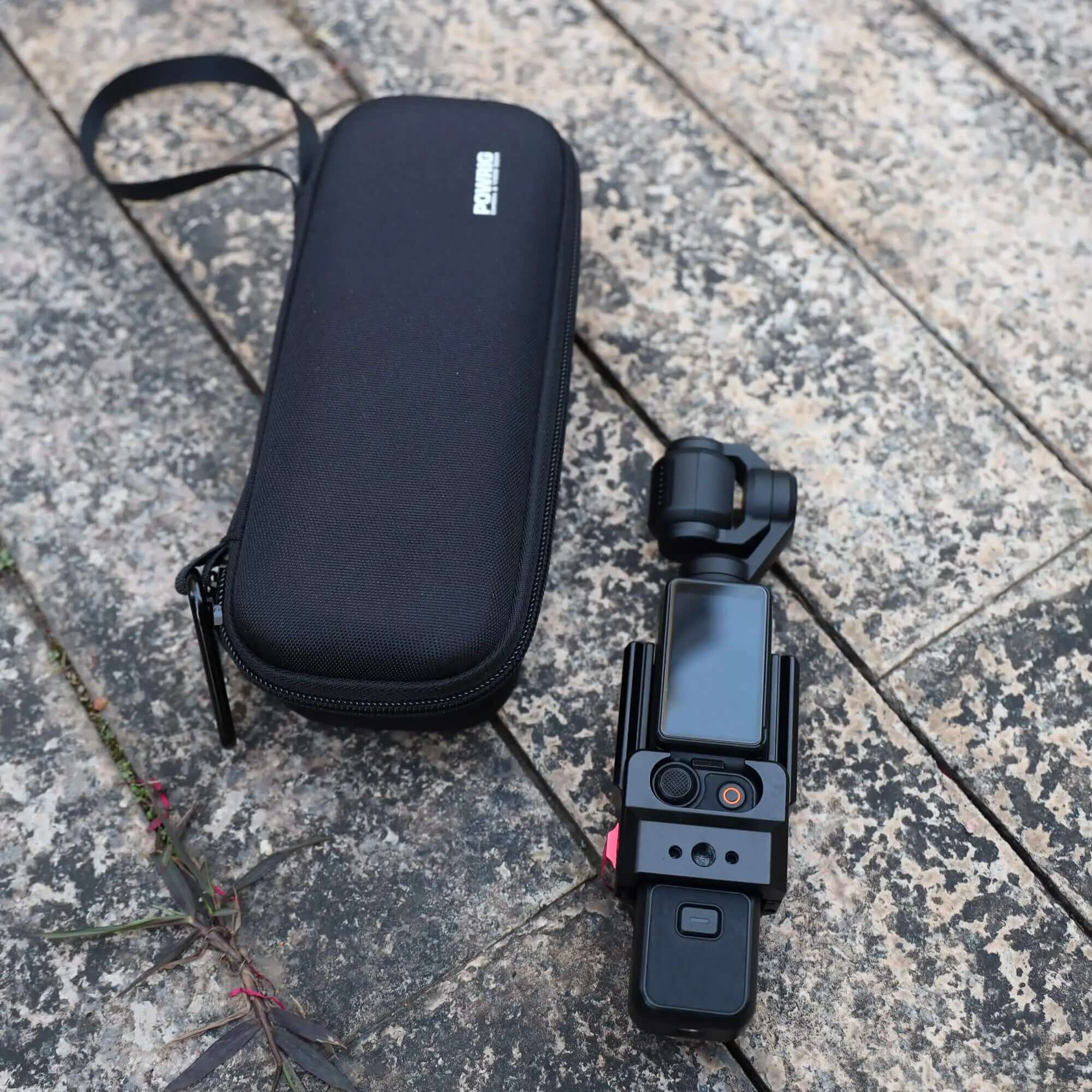 Black carrying pouch with wrist strap lying next to DJI Osmo Pocket gimbal